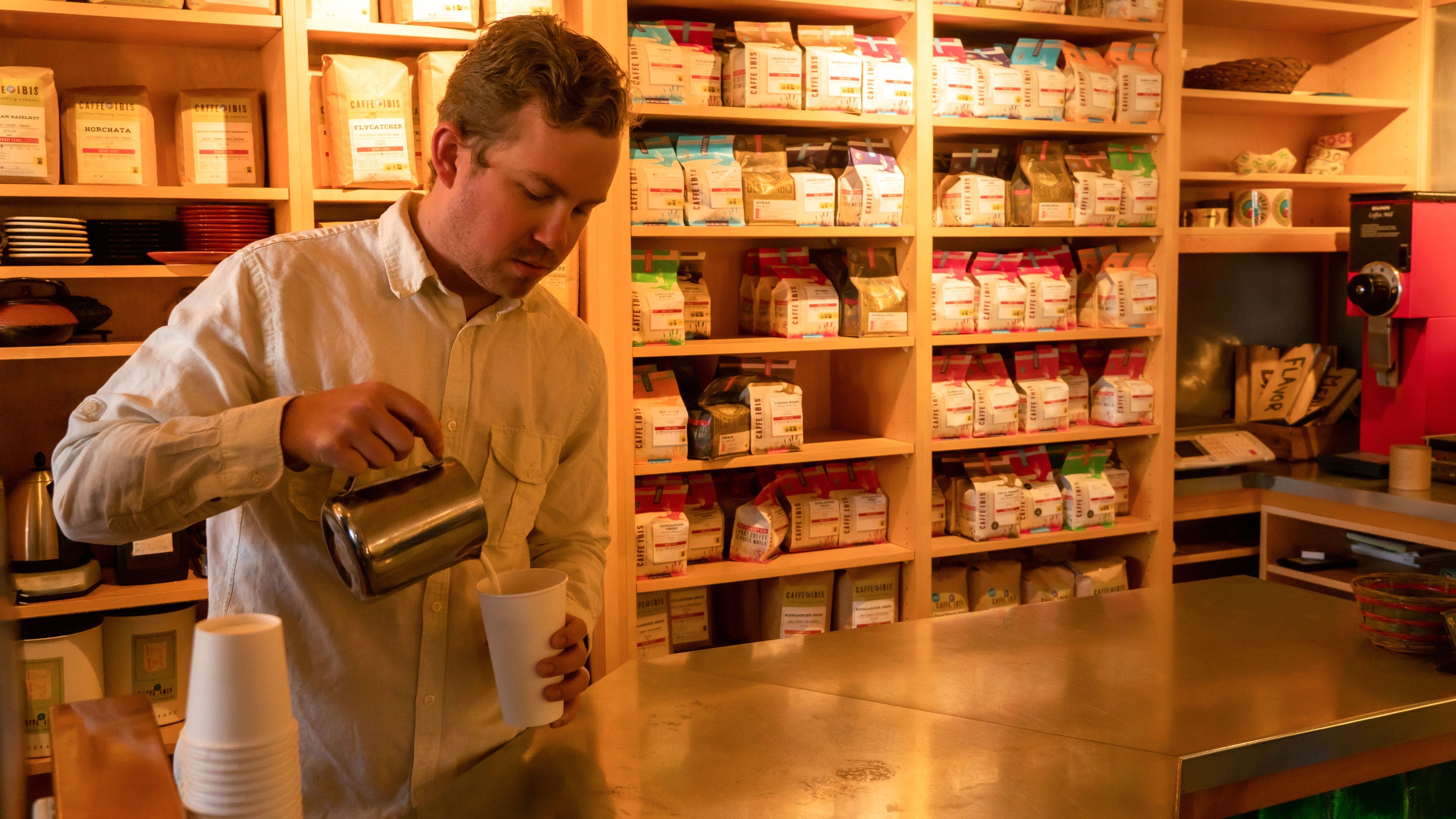 Caffe Ibis barista pouring milk into a to-go cup.