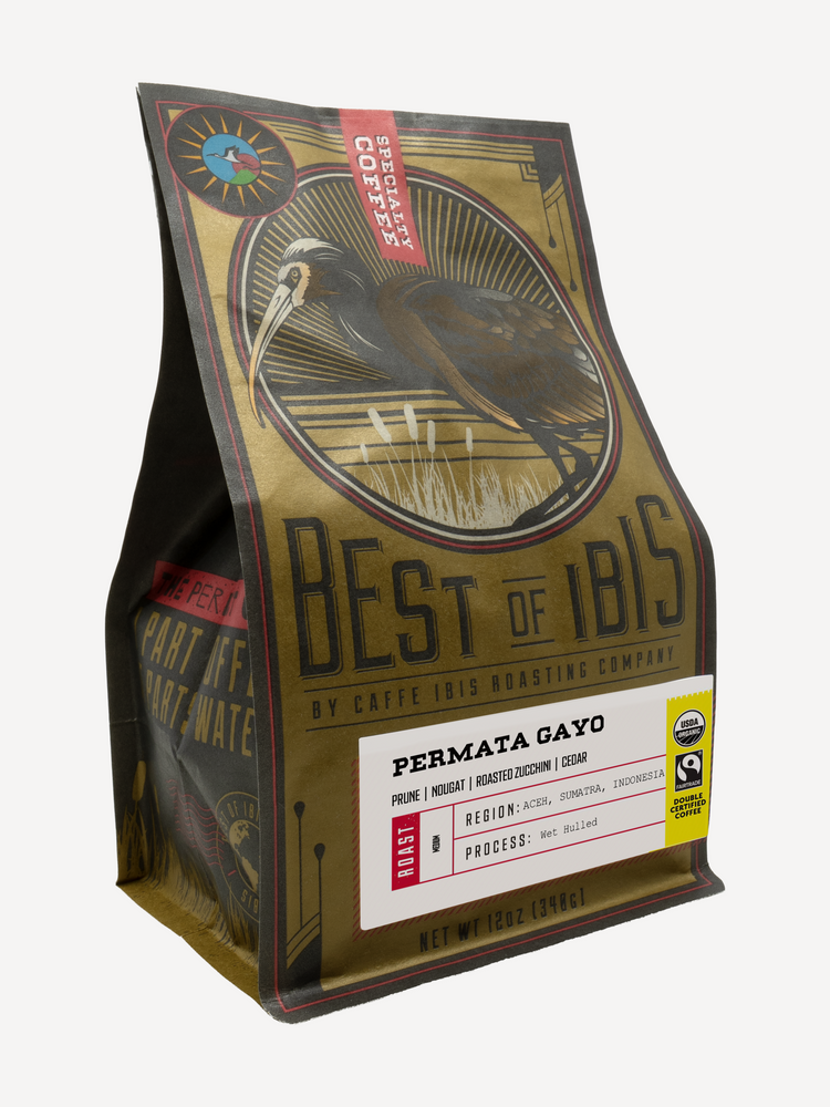 A bag of coffee from Best of 1Bis Roasting Company, specifically Permata Gayo. The packaging is a metallic gold and dark brown matte board with a detailed illustration of a white-faced ibis in a circular frame.