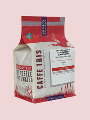 Caffe Ibis Decaf Sally's Cinnamon Hazelnut & Crème flavored coffee in a pink twelve ounce bag; front quarter view.