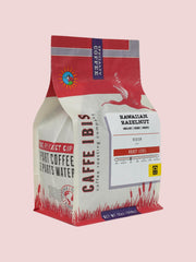 Caffe Ibis flavored Hawaiaan Hazelnut coffee in a pink twelve ounce bag; front quarter view.