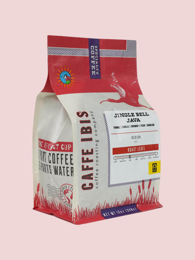 Caffe Ibis seasonal flavored Jingle Bell Java coffee in a pink twelve ounce bag; front quarter view.