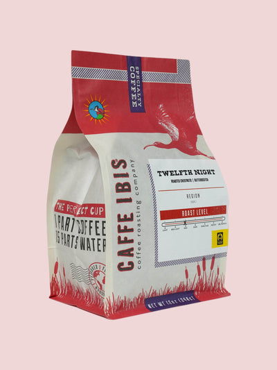 Caffe Ibis seasonal flavored Twelfth Night (Holiday Chestnut) coffee in a pink twelve ounce bag; front quarter view.